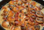 Émincés de poulet à la moutarde, lardons et champignons dans une sauce crémeuse, servis avec une écrasée de pommes de terre.
