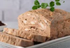 Terrine de poulet tranchée, garnie de légumes colorés et servie avec une salade verte.