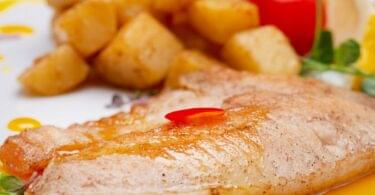 Filet de poisson grillé servi avec citron, persil frais et légumes grillés.